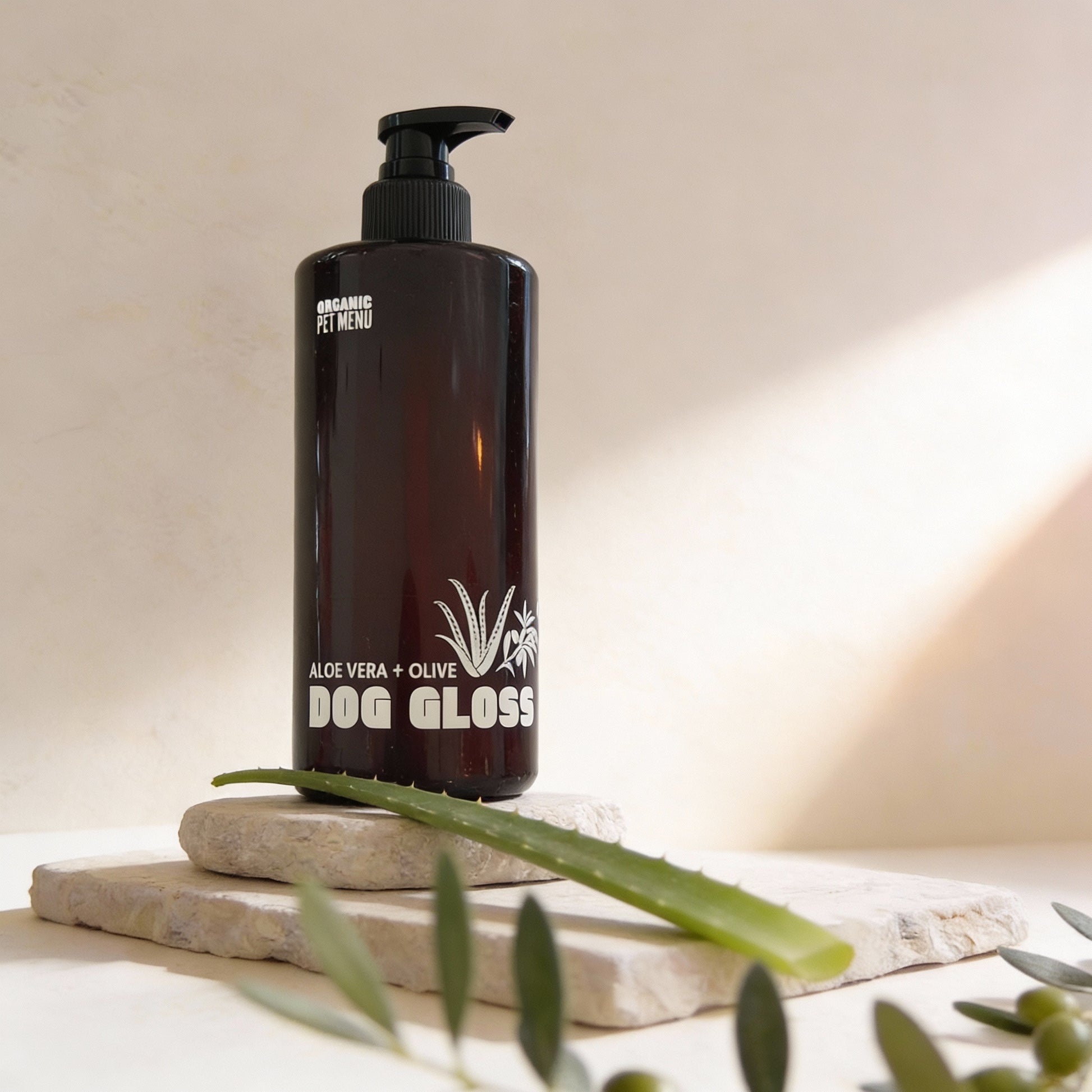 Black bottle of Dog Gloss with aloe vera and olive on a neutral background